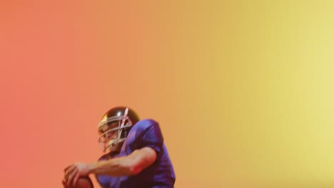 Video-of-close-up-of-caucasian-american-football-player-in-helmet-with-ball-over-orange-background
