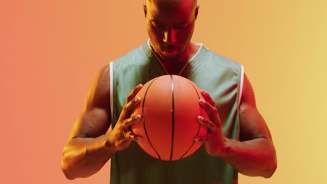 Video-Eines-Afroamerikanischen-Männlichen-Basketballspielers,-Der-Ball-Auf-Orangefarbenem-Hintergrund-Hält