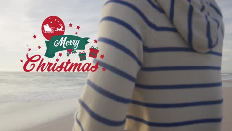 Animation-of-merry-christmas-text-over-biracial-couple-at-beach