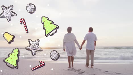 Animation-of-christmas-icons-over-senior-biracial-couple-at-beach