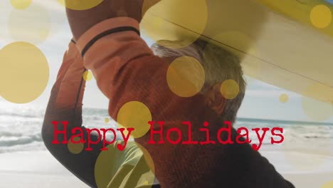 Animation-of-happy-holidays-text-and-light-spots-over-senior-biracial-woman-at-beach