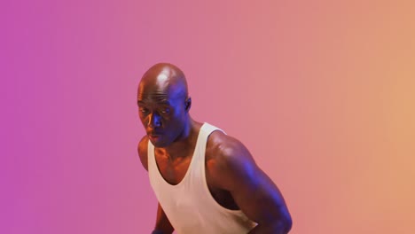 Video-of-african-american-male-basketball-player-throwing-ball-on-pink-to-orange-background