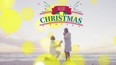 Animation-of-merry-christmas-text-and-light-spots-over-senior-biracial-couple-at-beach