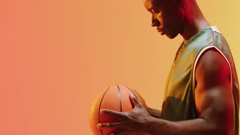 Video-Eines-Afroamerikanischen-Männlichen-Basketballspielers,-Der-Einen-Ball-Auf-Orangefarbenem-Hintergrund-Dreht