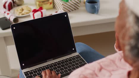 Happy-senior-african-american-woman-having-video-call-using-laptop-with-copy-space-at-christmas
