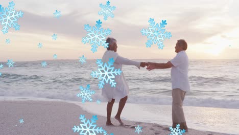 Animation-of-snow-falling-over-senior-biracial-couple-at-beach