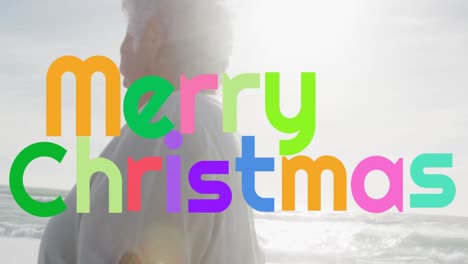 Animation-of-merry-christmas-text-over-senior-biracial-couple-at-beach