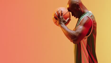 Video-of-african-american-male-basketball-player-holding-ball-on-orange-background