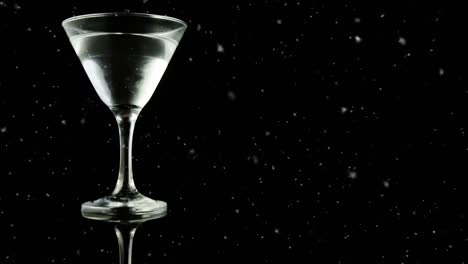 Animation-of-snow-falling-over-drink-in-glass-on-black-background