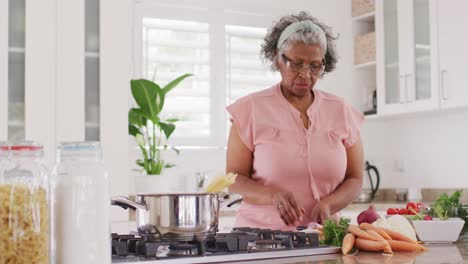 Feliz-Anciana-Afroamericana-Cocinando-En-La-Cocina,-Cortando-Verduras