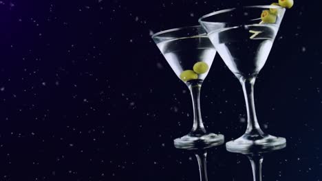 Animation-of-snow-falling-over-drinks-with-olives-on-black-background