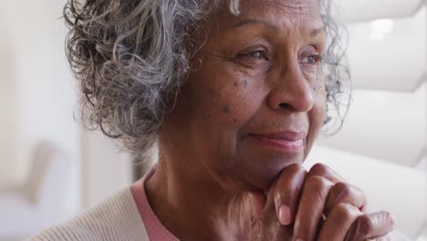 Glückliche-ältere-Afroamerikanische-Frau,-Die-Durch-Das-Fenster-Schaut