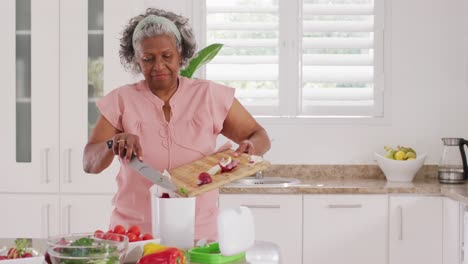 Glückliche-ältere-Afroamerikanische-Frau,-Die-In-Der-Küche-Kocht-Und-Abfälle-Entsorgt