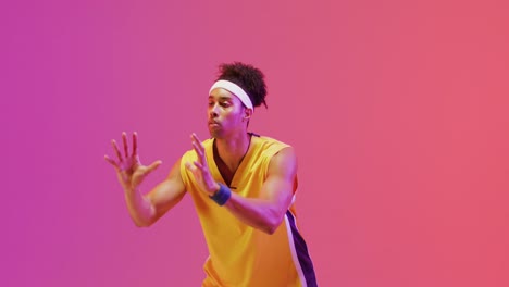 Video-Eines-Gemischtrassigen-Männlichen-Basketballspielers,-Der-Den-Ball-Auf-Orangefarbenem-Bis-Rosafarbenem-Hintergrund-Fängt