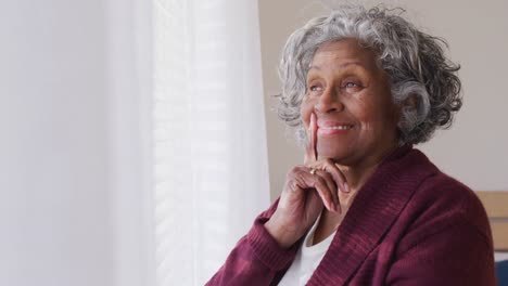 Happy-senior-african-american-woman-looking-through-window