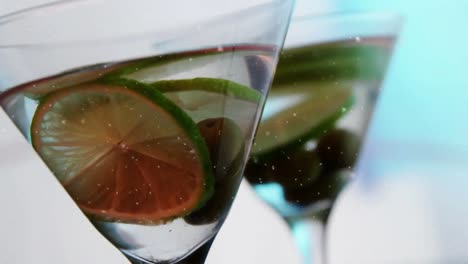 Animation-of-snow-falling-over-drink-with-olives-and-lime