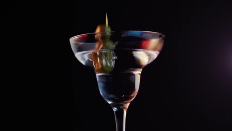Animation-Violetter-Formen-über-Einem-Getränk-Mit-Oliven-Auf-Schwarzem-Hintergrund