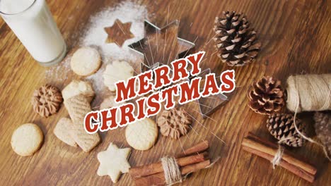 Animation-of-merry-christmas-over-cookies-and-decorations-on-wooden-surface