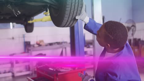Animation-Von-Lichtspuren-über-Einem-Afroamerikanischen-Männlichen-Mechaniker,-Der-Ein-Auto-Repariert