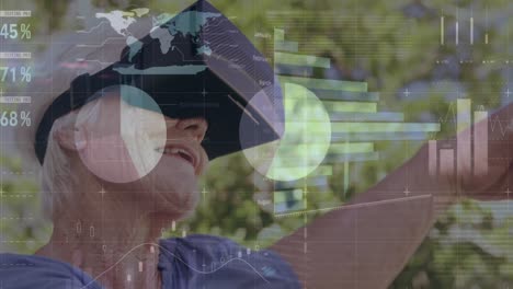 Animation-of-numbers-and-statistics-over-senior-caucasian-woman-wearing-vr-headset
