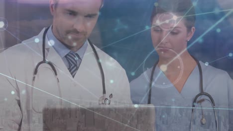 Animation-of-network-of-connections-over-caucasian-male-and-female-doctors-using-laptop
