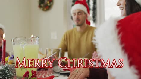 Animation-of-merry-christmas-text-over-happy-caucasian-family-in-santa-hats-saying-grace-at-dinner