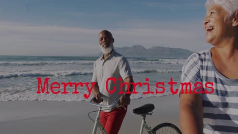 Animation-Von-Weihnachtsgrüßen-über-Ein-älteres-Gemischtrassiges-Paar-Mit-Fahrrädern-Am-Strand