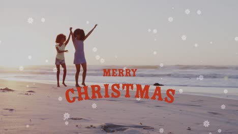 Animation-of-merry-christmas-text-over-happy-african-american-mother-and-daughter-on-sunny-beach