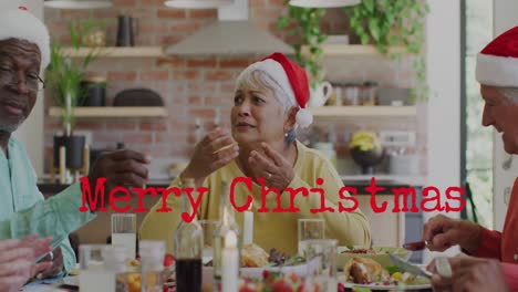 Animation-of-merry-christmas-over-happy-diverse-senior-friends-in-santa-hats-eating-together