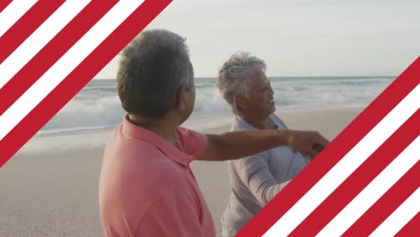 Animation-of-flag-of-united-states-of-america-over-senior-biracial-couple-dancing-on-beach