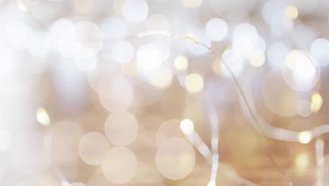 Animation-of-defocussed-white-light-spots-moving-over-glowing-christmas-fairy-lights