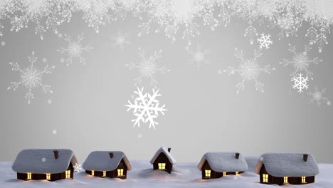 Animation-of-white-christmas-snowflakes-falling-over-cottages-in-winter-landscape