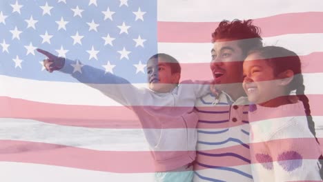 Animation-of-flag-of-united-states-of-america-over-biracial-father-with-son-and-daughter-by-seaside