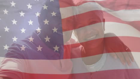 Animation-of-flag-of-united-states-of-america-over-happy-senior-biracial-couple-embracing-on-beach