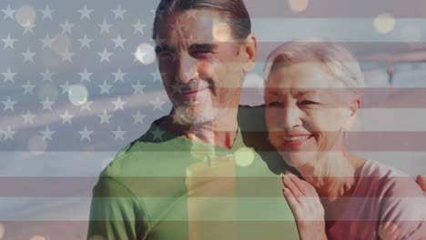 Animation-of-flag-of-united-states-of-america-over-senior-caucasian-couple-on-beach