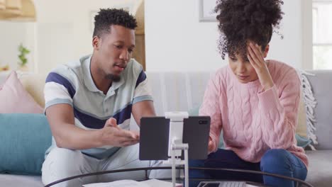 Afroamerikanisches-Paar-Mit-Dokumenten-Und-Tablet-Im-Wohnzimmer