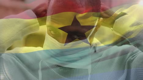 Animation-of-flag-of-ghana-over-african-american-man-with-face-mask