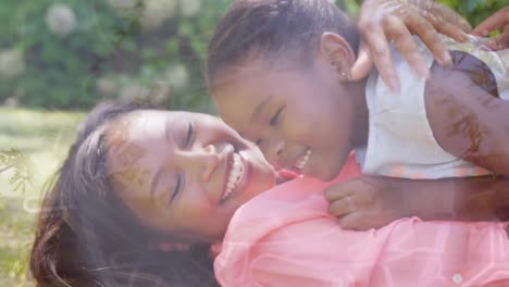 Animation-of-african-american-mother-and-daughter-embracing-in-park-over-leaves
