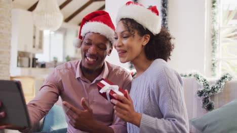 Glückliches-Afroamerikanisches-Paar-Mit-Weihnachtsmützen-Beim-Tablet-Videoanruf
