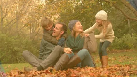 Animation-of-caucasian-family-smiling-in-park-over-leaves