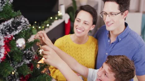 Felices-Padres-Caucásicos-E-Hijo-Decorando-El-árbol-De-Navidad-En-Navidad