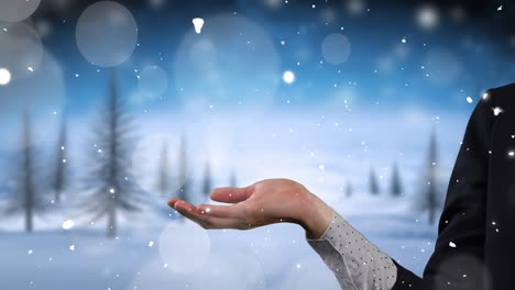 Animation-of-snow-falling-over-hands-of-caucasian-woman-and-winter-landscape