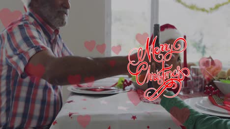 Animation-of-merry-christmas-over-african-american-grandfather-and-grandchildren-at-table