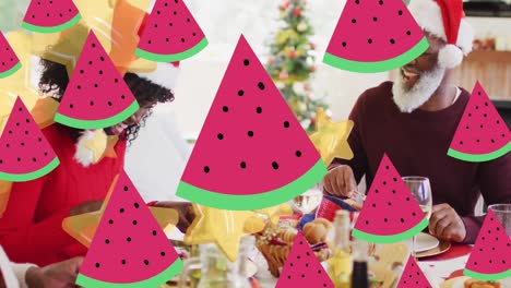 Animation-Von-Sternen-über-Einer-Afroamerikanischen-Familie-Mit-Weihnachtsmützen-Beim-Weihnachtsessen