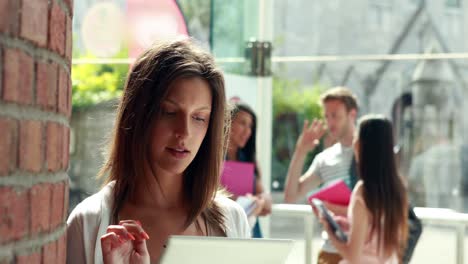 Student-using-tablet-and-friends-speaking-behind-her