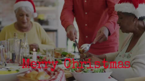 Animation-of-christmas-greetings-text-over-diverse-friends-at-christmas-meal-table