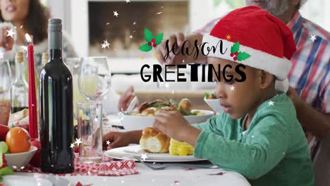 Animation-of-christmas-greetings-text-over-african-american-boy-at-christmas-meal-table