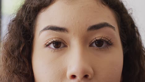Close-up-video-portrait-of-opening-eyes-of-biracial-woman-smiling-to-camera-indoors