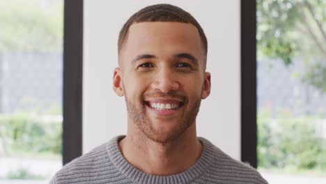 Video-portrait-of-biracial-man-smiling-to-camera-indoors