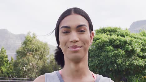 Video-portrait-of-happy-biracial-non-binary-transgender-woman-smiling-to-camera-outdoors
